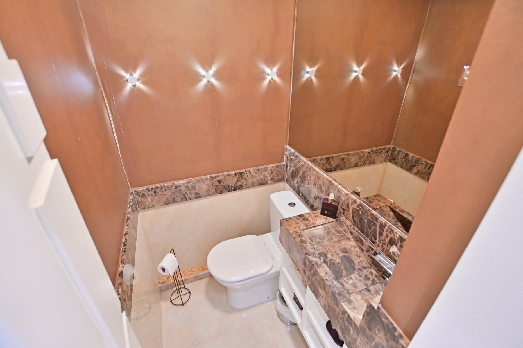Lavabo revestido em mármore, com bancada e cuba esculpida