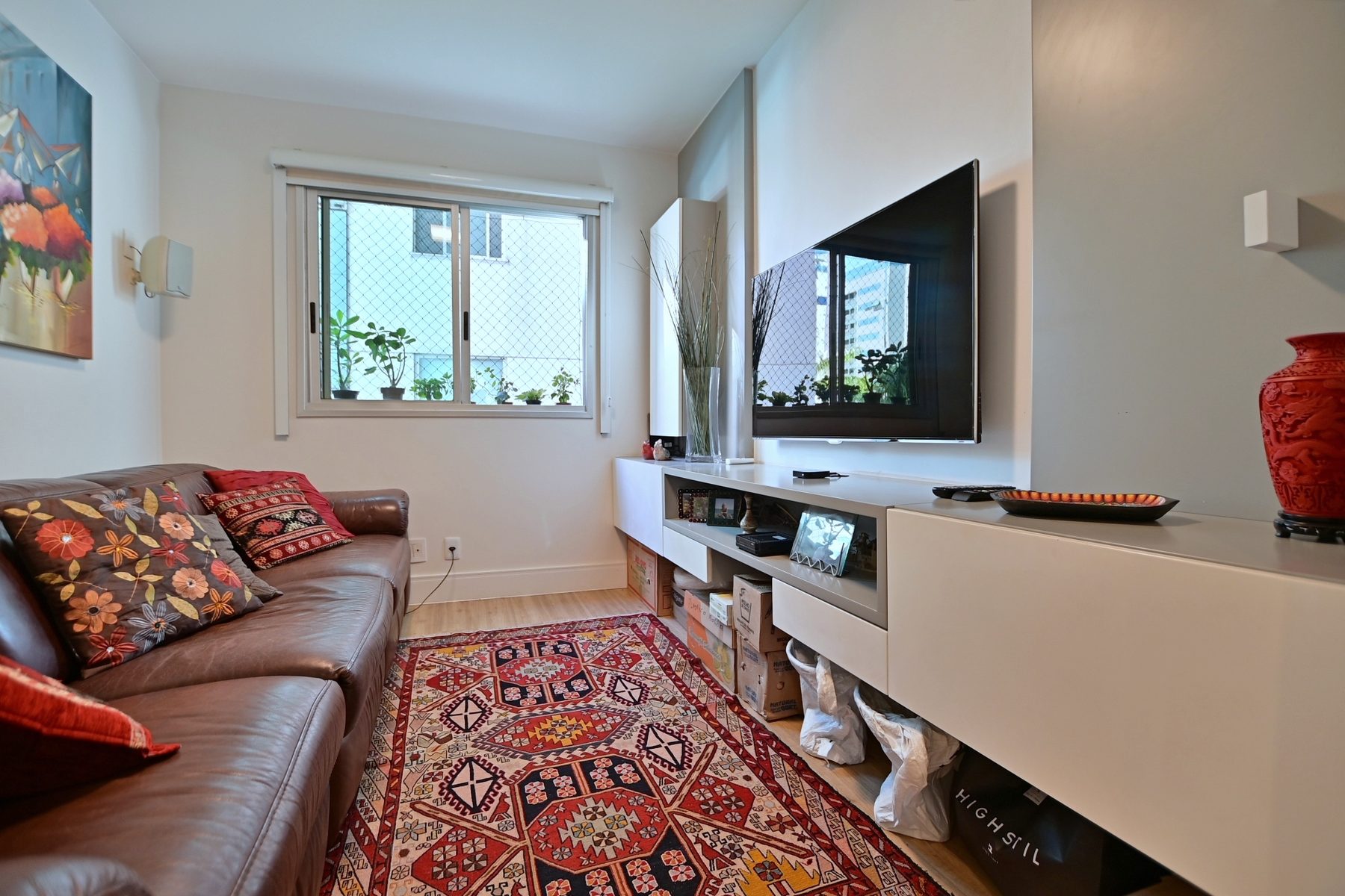 Quarto convertido em sala de televisão, com sofá e painel de TV
