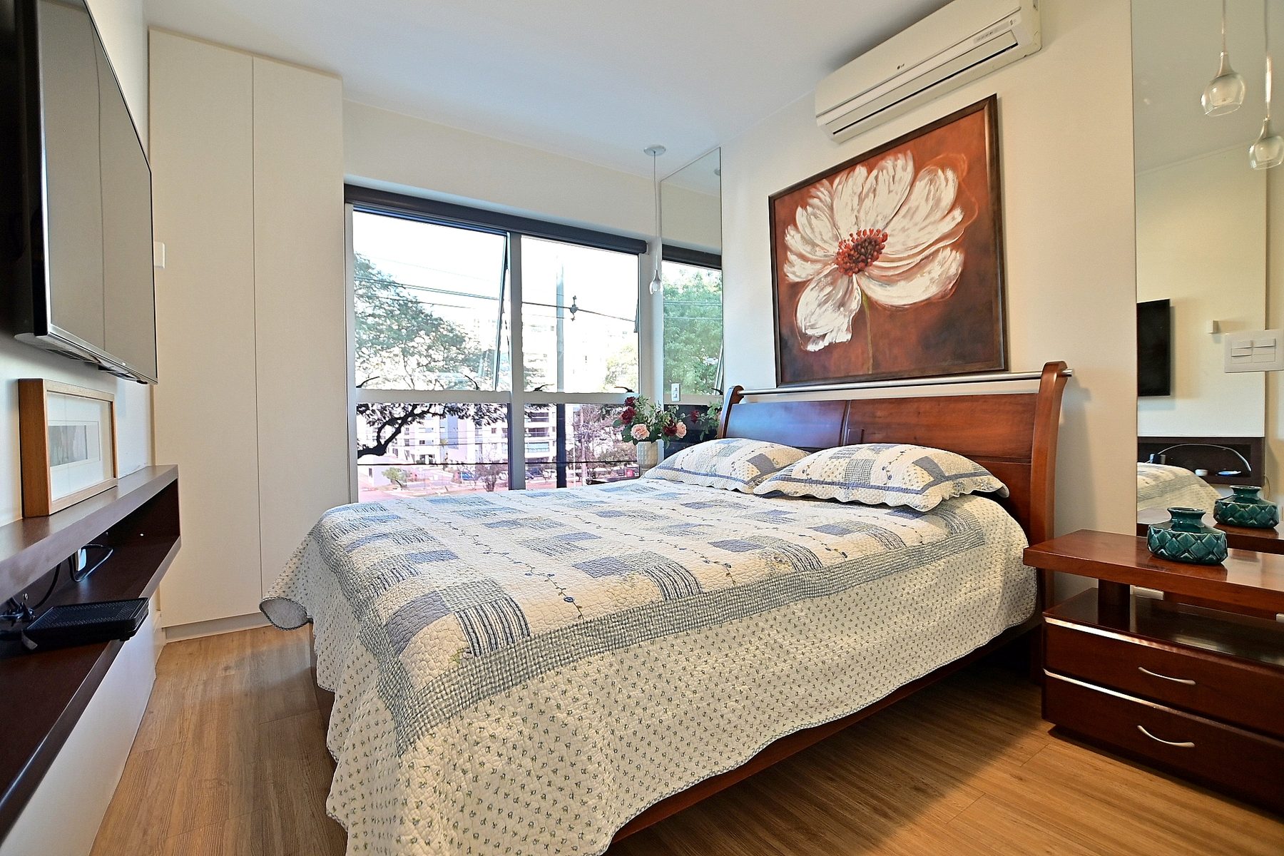 Suíte principal com cama de casal, piso de madeira e sacada própria